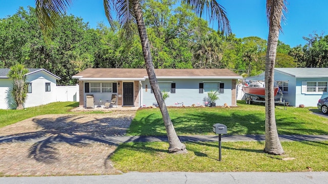 ranch-style house with decorative driveway and a front lawn