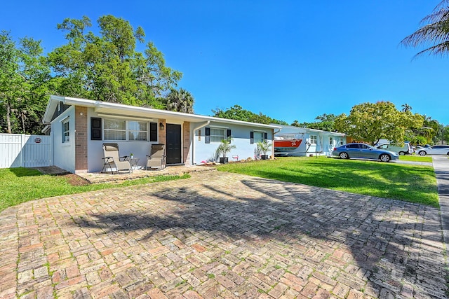 single story home with a front lawn, fence, and brick siding