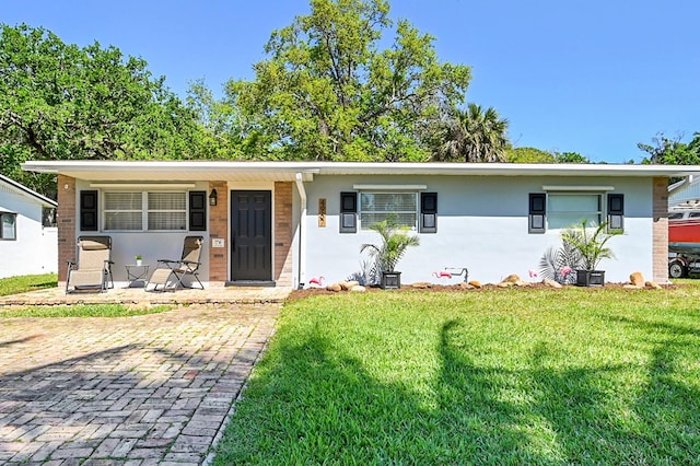 ranch-style home with stucco siding and a front lawn