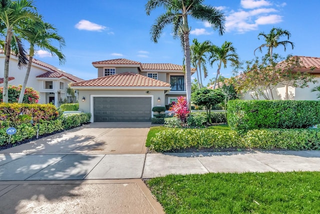 mediterranean / spanish home with a tile roof, stucco siding, an attached garage, and concrete driveway