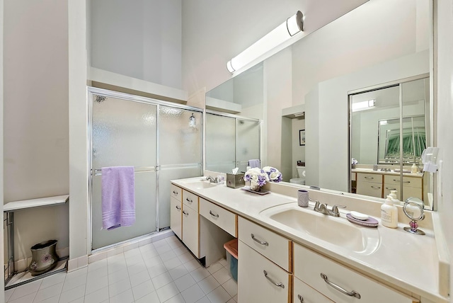 bathroom featuring a shower stall, toilet, double vanity, and a sink