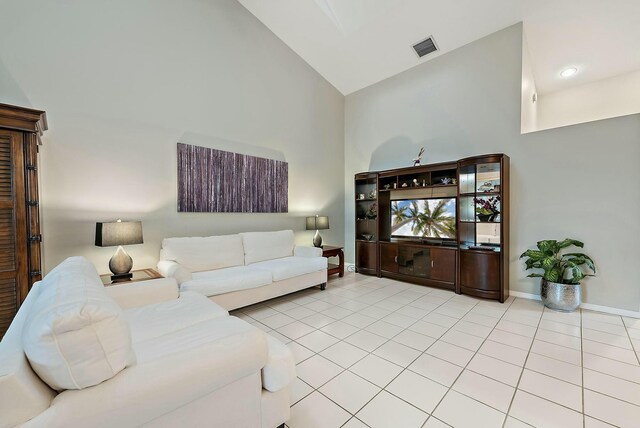 tiled living area featuring visible vents, baseboards, and high vaulted ceiling