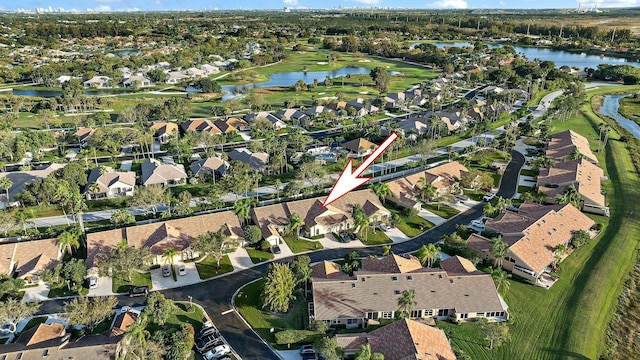 drone / aerial view featuring golf course view, a water view, and a residential view