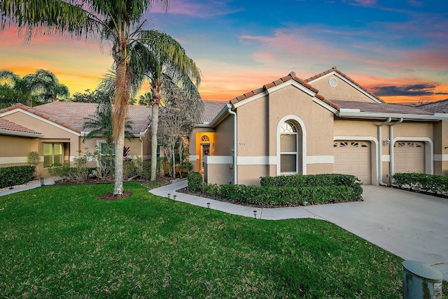 view of front of property with stucco siding, a front lawn, a tile roof, concrete driveway, and a garage