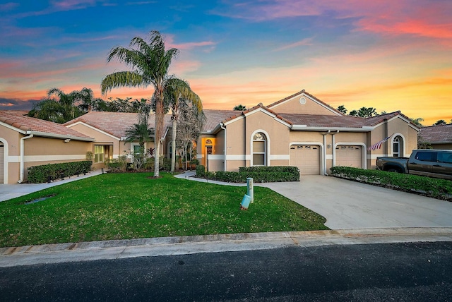 ranch-style home featuring driveway, an attached garage, a yard, stucco siding, and a tiled roof