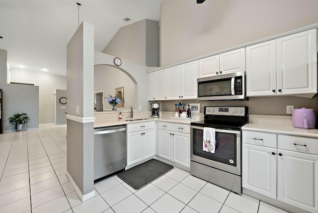 kitchen with a sink, light tile patterned flooring, high vaulted ceiling, light countertops, and appliances with stainless steel finishes