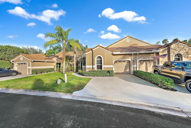 mediterranean / spanish house featuring concrete driveway, a tiled roof, a front yard, stucco siding, and a garage