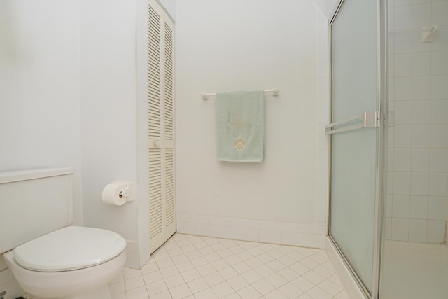 full bathroom with a closet, toilet, a stall shower, and tile patterned flooring