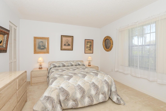 bedroom with a closet, light colored carpet, and a textured ceiling