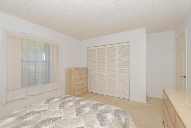 bedroom featuring a closet, light carpet, a textured ceiling, and baseboards