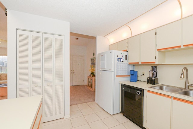 kitchen with light tile patterned flooring, freestanding refrigerator, a sink, light countertops, and black dishwasher