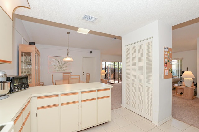 kitchen with visible vents, pendant lighting, light countertops, light carpet, and a peninsula