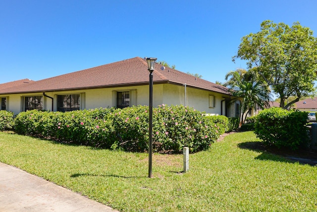 view of side of home with stucco siding and a lawn