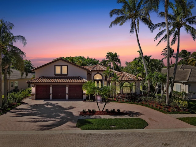 mediterranean / spanish house with stucco siding, a tile roof, and decorative driveway