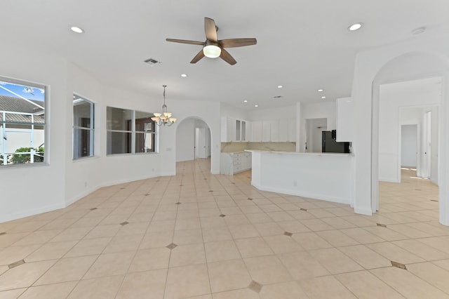 kitchen featuring visible vents, black refrigerator, recessed lighting, ceiling fan with notable chandelier, and white cabinetry