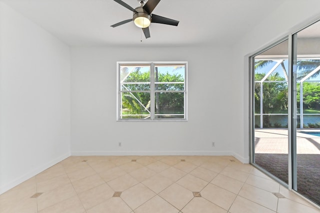 unfurnished room featuring light tile patterned flooring, a ceiling fan, and baseboards