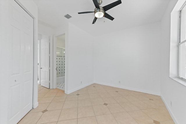 spare room featuring light tile patterned floors, visible vents, baseboards, and a ceiling fan