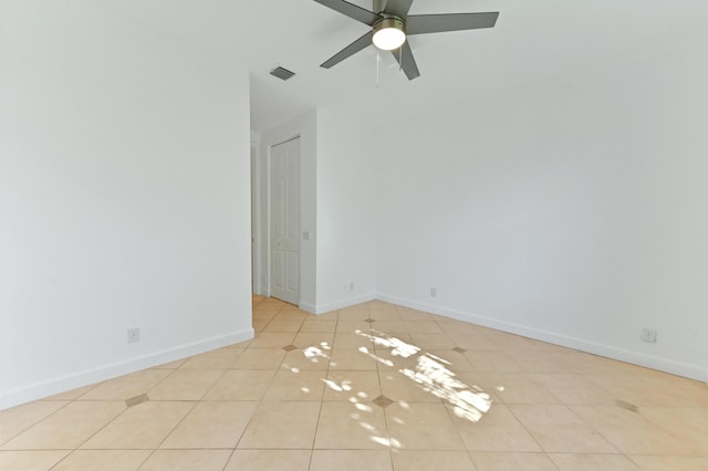 tiled spare room featuring visible vents, baseboards, and ceiling fan