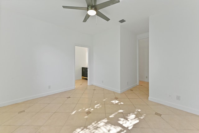 tiled spare room with visible vents, ceiling fan, and baseboards