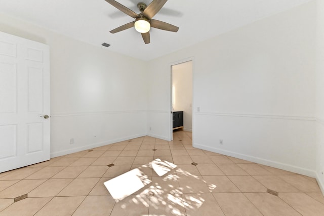 tiled empty room featuring a ceiling fan, baseboards, and visible vents