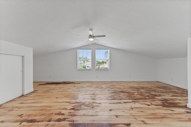 bonus room with vaulted ceiling, wood finished floors, and a textured ceiling