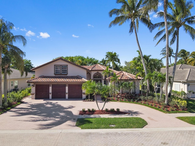 mediterranean / spanish home with a tiled roof, decorative driveway, and stucco siding