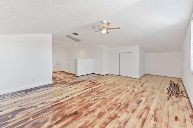 bonus room with a textured ceiling, wood finished floors, baseboards, and vaulted ceiling