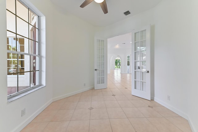 unfurnished room featuring visible vents, french doors, arched walkways, tile patterned flooring, and baseboards