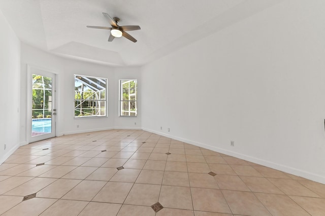 spare room featuring light tile patterned floors, baseboards, a tray ceiling, and ceiling fan