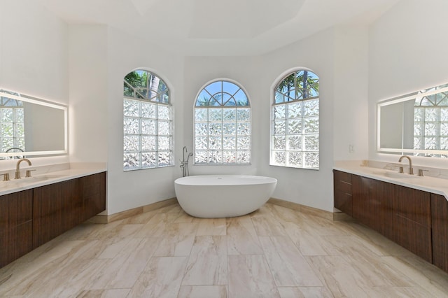 bathroom with a freestanding bath, two vanities, and a sink