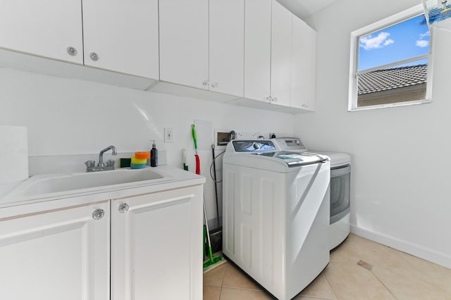 laundry area featuring light tile patterned floors, baseboards, cabinet space, a sink, and washer and dryer