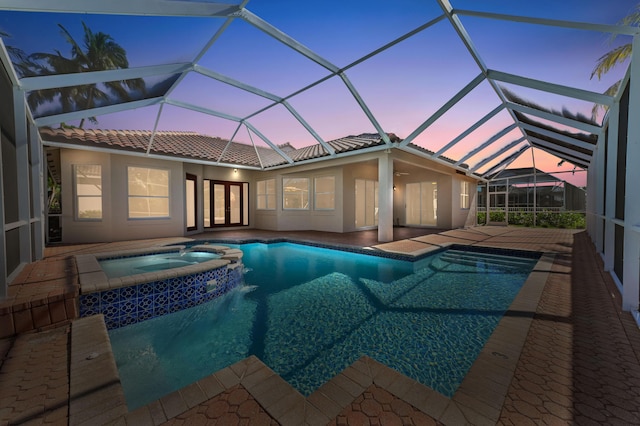 pool at dusk with a pool with connected hot tub, a patio, french doors, glass enclosure, and ceiling fan