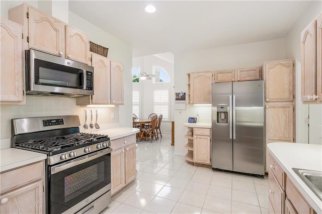 kitchen featuring tasteful backsplash, appliances with stainless steel finishes, light brown cabinetry, and light countertops