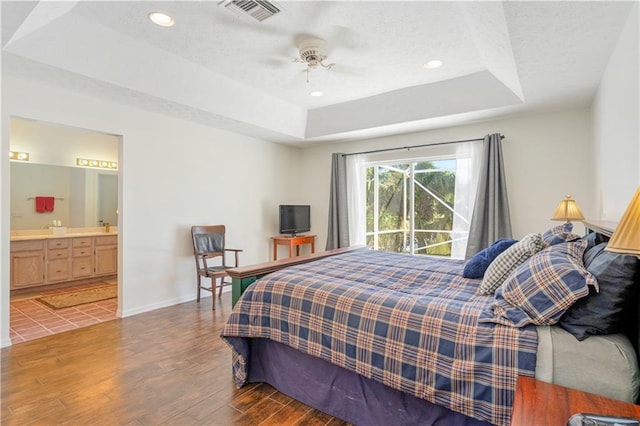 bedroom with visible vents, a textured ceiling, a raised ceiling, and wood finished floors