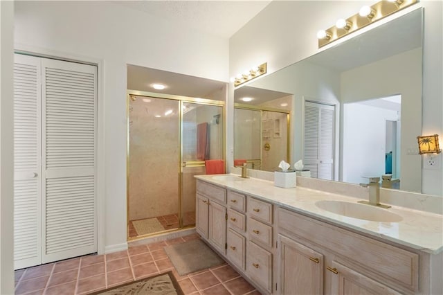 full bathroom featuring a closet, tile patterned flooring, a shower stall, and a sink