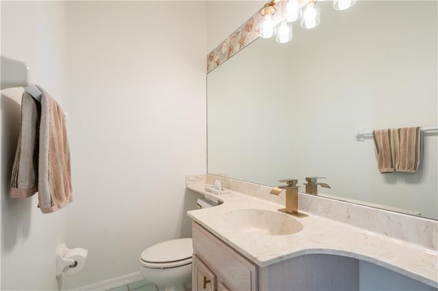 half bath featuring vanity, toilet, and baseboards