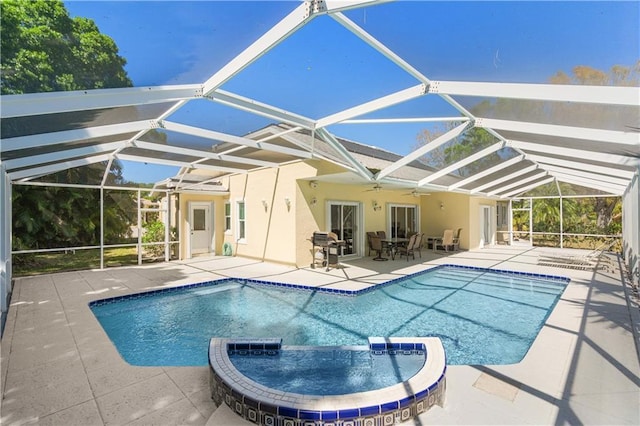 view of pool featuring a pool with connected hot tub, ceiling fan, a lanai, a patio area, and a grill