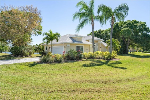 view of front of property featuring a garage, driveway, a front yard, and stucco siding