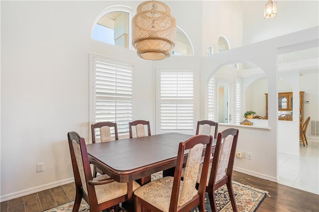 dining area with a towering ceiling, baseboards, and wood finished floors