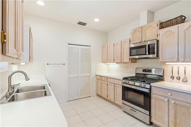 kitchen with a sink, light brown cabinetry, light countertops, appliances with stainless steel finishes, and backsplash