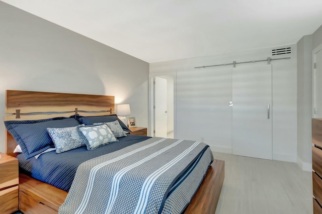 bedroom featuring a closet, baseboards, visible vents, and wood finished floors