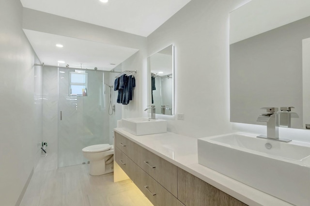 full bath with a marble finish shower, double vanity, toilet, and a sink