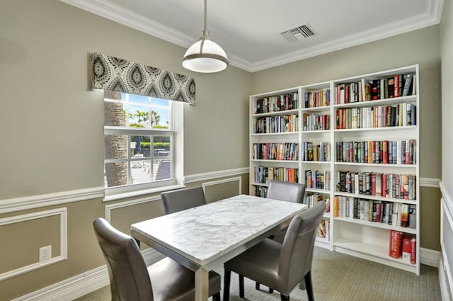 dining area with a wainscoted wall, carpet, visible vents, and ornamental molding