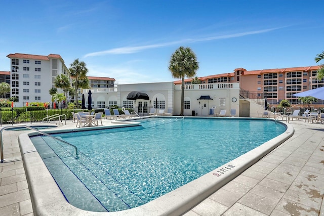 community pool with a patio and fence