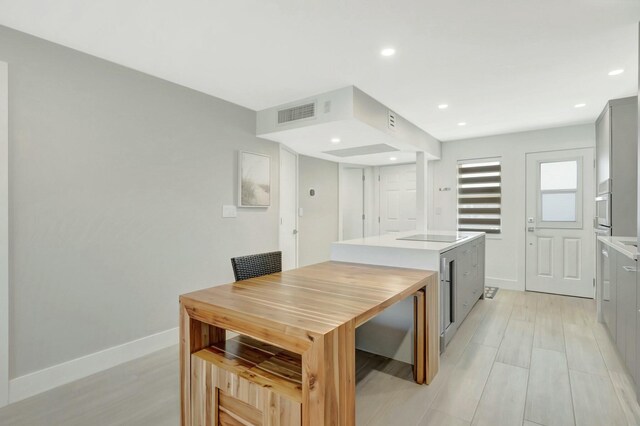 kitchen with baseboards, visible vents, oven, light countertops, and a center island