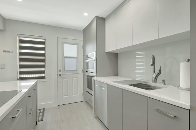 kitchen featuring double oven, light countertops, gray cabinets, modern cabinets, and a sink