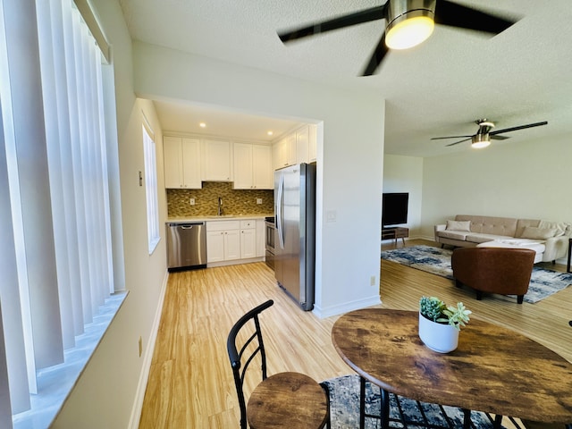 230 Normandy Ln E, Delray Beach, FL 33484 - kitchen featuring stainless steel appliances, ceiling fan, white cabinetry, a sink, and light wood finished floors