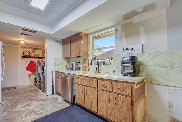 kitchen with stainless steel dishwasher, light countertops, a sink, and washer and clothes dryer