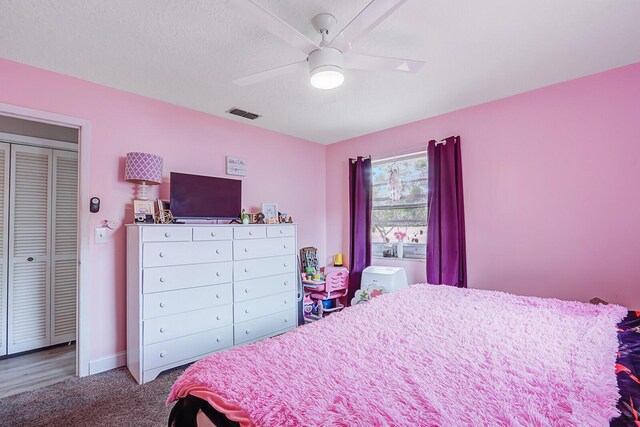 carpeted bedroom featuring a textured ceiling, a ceiling fan, visible vents, and baseboards