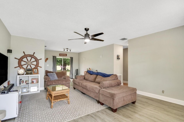 living room with wood finished floors, baseboards, visible vents, and a textured ceiling